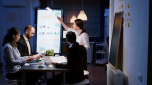 A bright, modern workspace featuring laptops, a camera, and a drawing tablet in an indoor office.